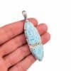 Colgante articulado de plata 925 con dos piedras de larimar sobre la mano, vista frontal
