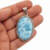 Colgante ovalado de larimar en plata 925 – sobre la mano Colgante ovalado de larimar azul en plata 925 sobre la mano, vista frontal para apreciar su tamaño